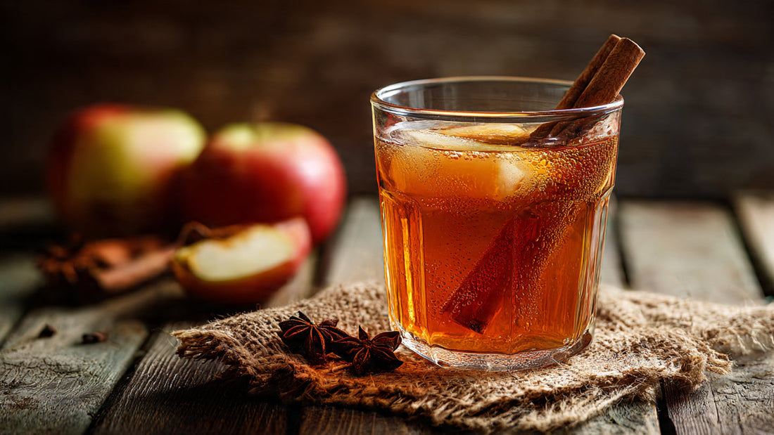 Iced apple rooibos tea in clear glass with cinnamon stick garnish on rustic wood table in warm autumn light