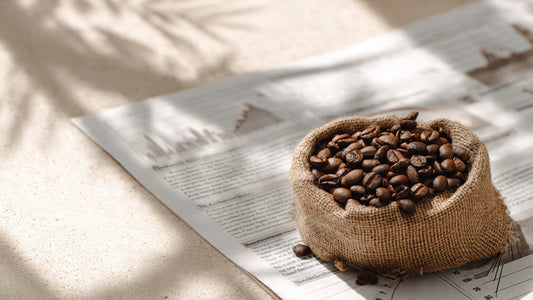 Editorial still life of roasted coffee beans on commodity market reports representing specialty coffee pricing and market trends.
