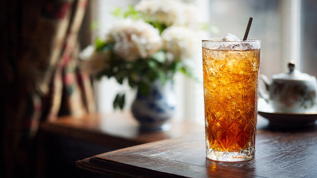 Iced English Breakfast tea in elegant glass on dark wood table with soft morning window light