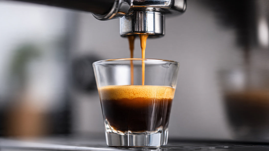 Fresh espresso shot with crema in a small glass cup on a clean neutral surface