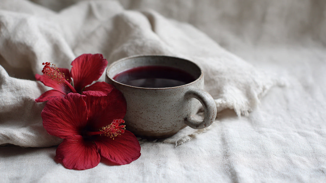 Hibiscus tea in ceramic cup with rich red color on neutral linen table in soft daylight