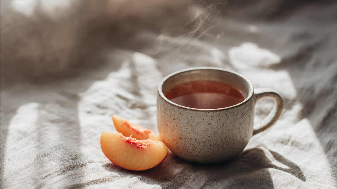 Peach tea in ceramic cup with soft steam and subtle peach slice on linen table in calm natural light