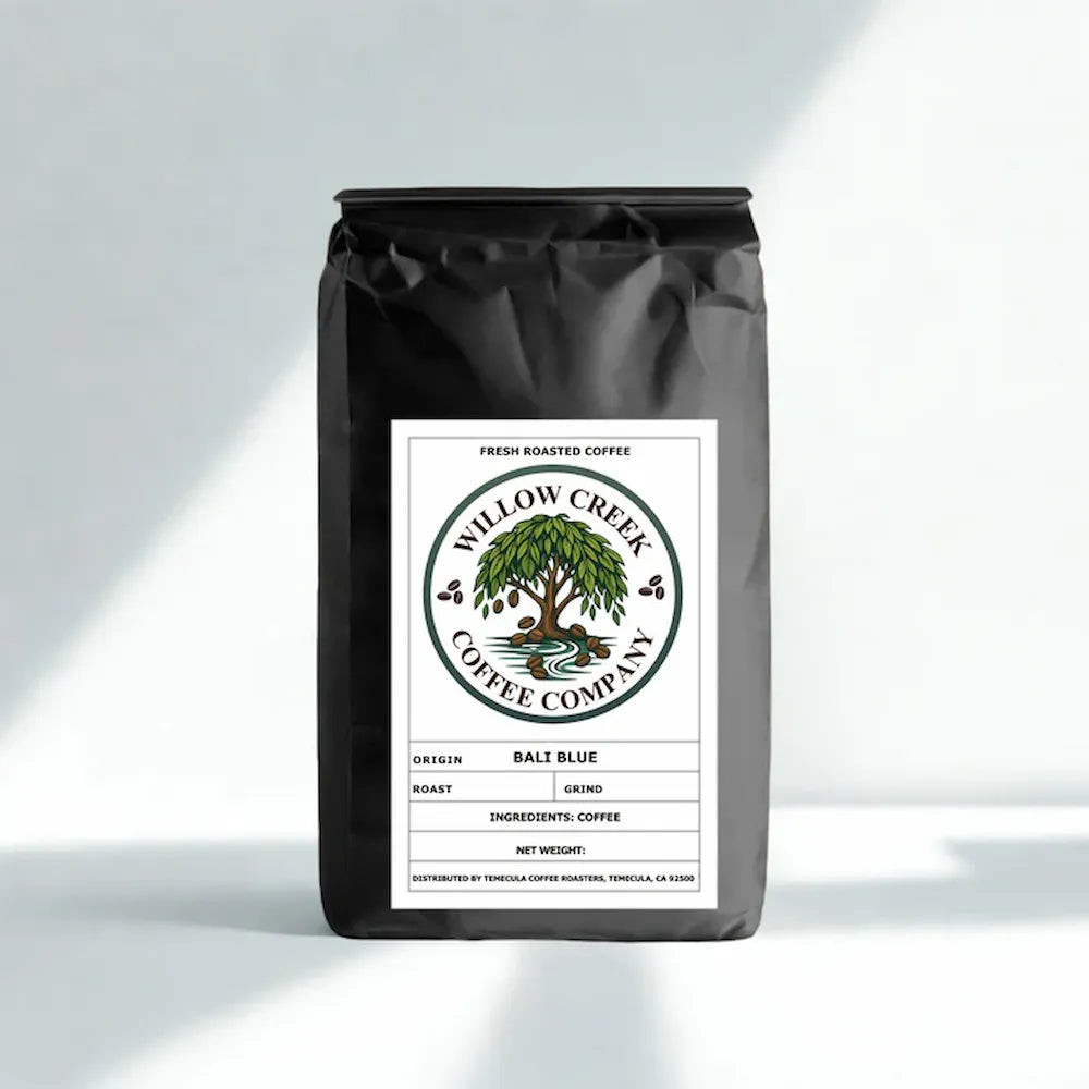 A black bag of Willow Creek Coffee Company Ball Blue fresh roasted coffee, standing upright on a light gray background with soft diagonal shadows.
