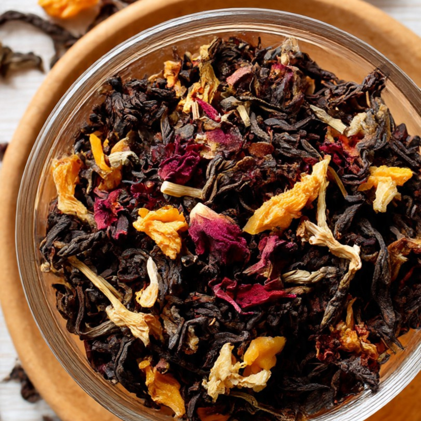 Assorted dried tea leaves in a glass jar with a wooden lid.