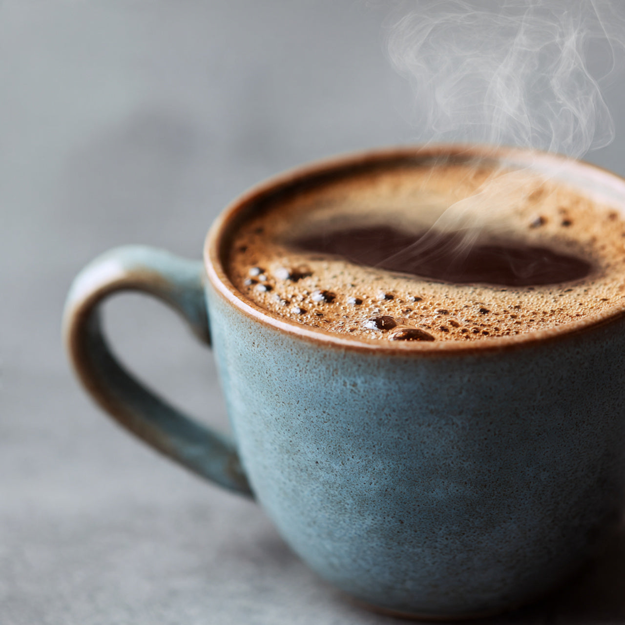 Steaming blue mug of smores coffee on a gray background