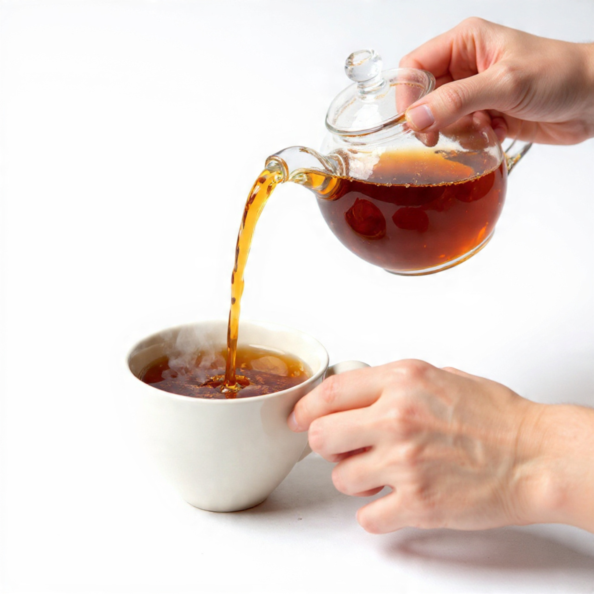 Person pouring english-breakfast tea from a glass teapot into a white cup on a white background