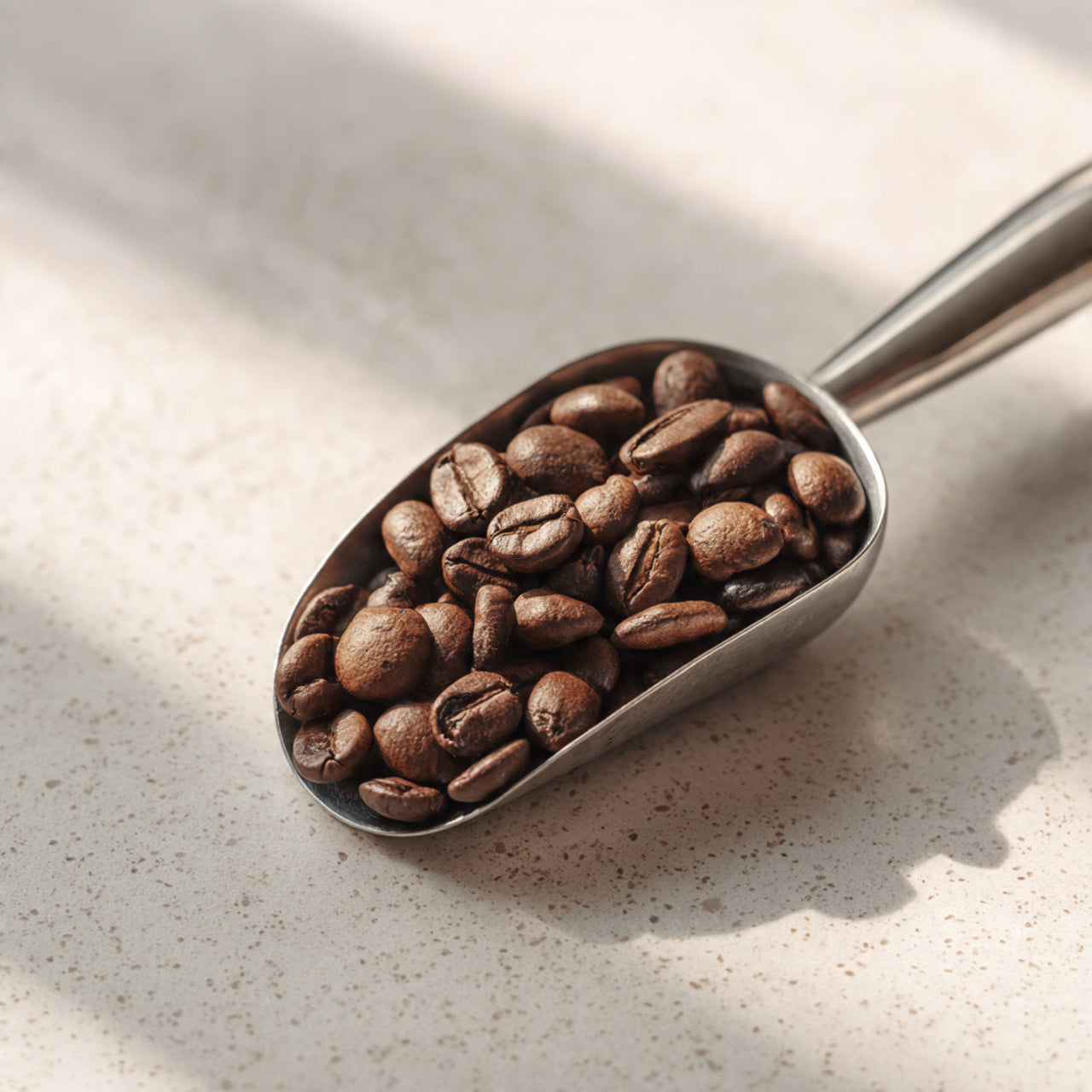 Metal scoop filled with french vanilla coffee beans on a light surface