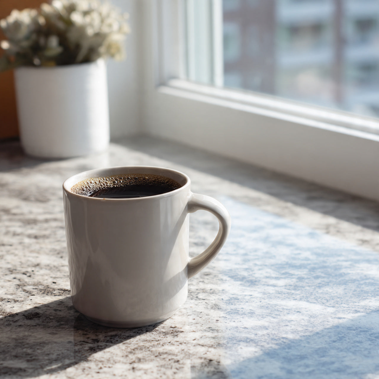 White mug with nicaragua coffee on a windowsill with sunlight and a plant in the background