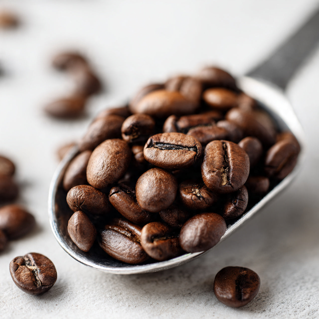 Spoonful of coffee house blend beans on a light surface