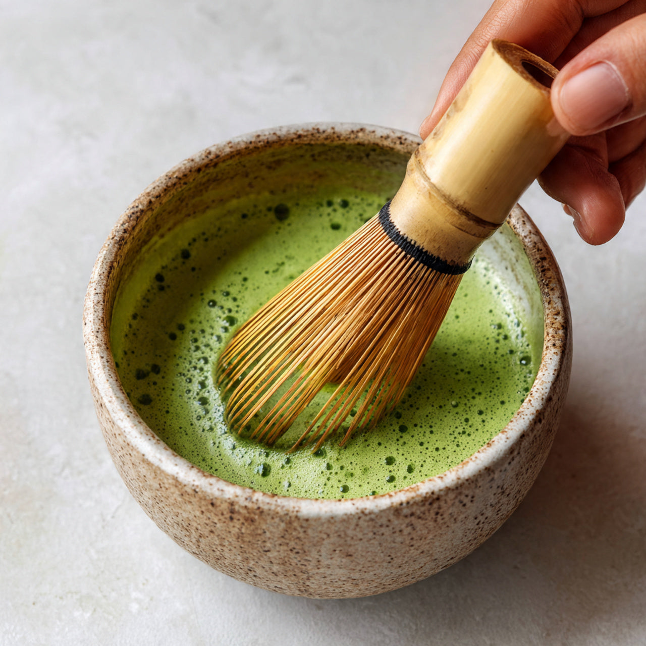 Matcha being whisked in bowl with bamboo whisk.