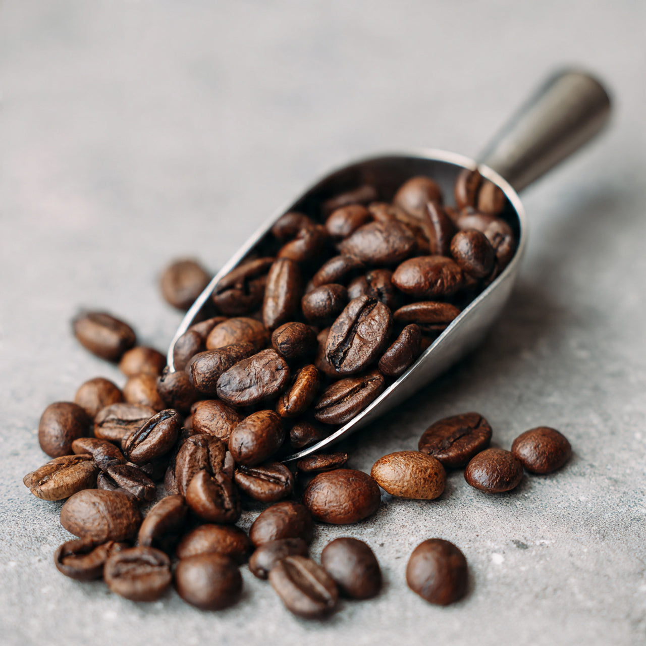 Silver scoop filled with papua new guinea coffee beans on a light gray surface