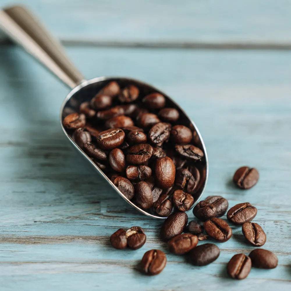 Metal scoop filled with sumatra coffee beans on a wooden surface