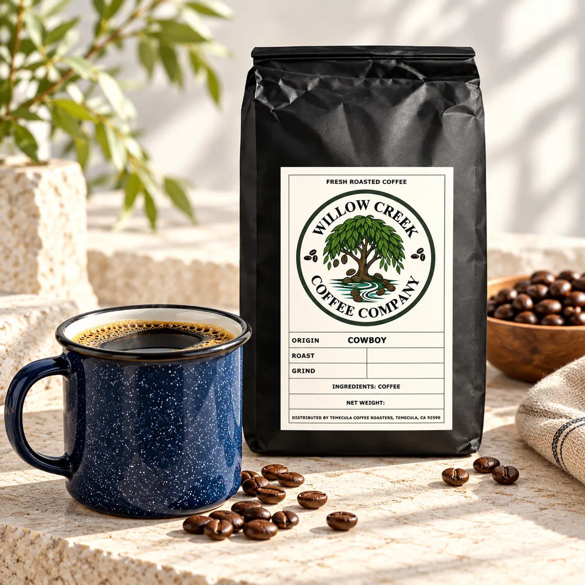 Willow Creek Coffee Company Cowboy Blend coffee bag on a light stone surface with scattered roasted coffee beans in soft natural light.